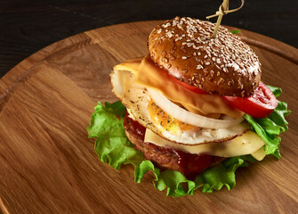 burger with meat cutlet, cheese, fried egg, tomatoes, cucumber slices and green lettuce, fast food