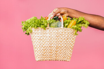 Delivery Concept - Handsome African American delivery man carrying package box of grocery food from store. Isolated on pink studio Background. Copy Space