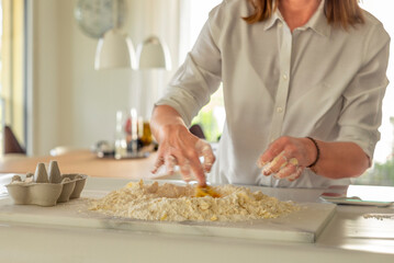 A woman making the dough for a sweet fruit tart at home in the kitchen