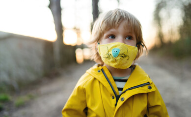 Small boy with face mask outdoors in nature, walking. © Halfpoint