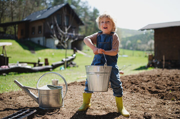 Small boy working outdoors in garden, sustainable lifestyle concept.