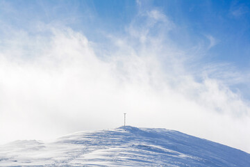 cross on the top of the mountain in hard winter