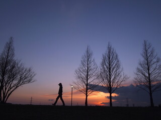 夕焼けを見ながら散歩している人のシルエット