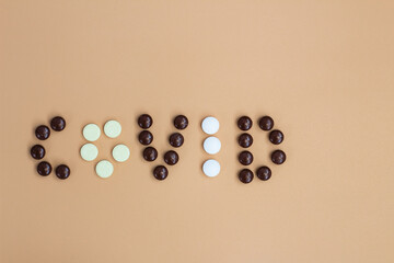 the word covid is made up of white and brown tablets. the view from the top