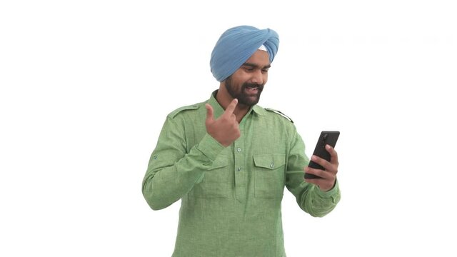 Young beard Indian man talking with friend by video call. Guy enjoying conversation, showing OK sign and emotionally gesticulating. Isolated on white background