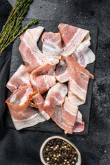 Smoked pork bacon with pepper and thyme. Organic raw meat. Black background. Top view