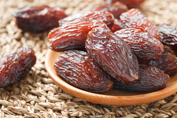 Date fruit in wood bowl on Wicker placemat, Dried date palm fruits top view