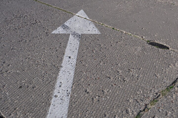 A direction sign is drawn on the concrete paving slabs.