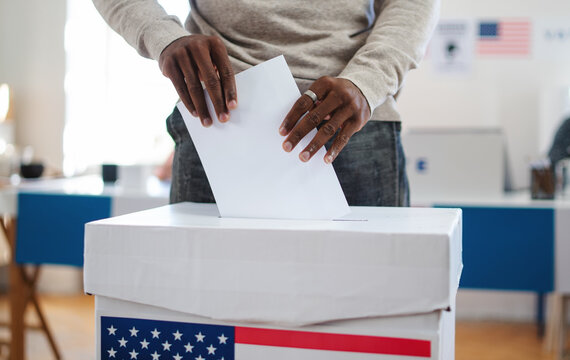 Unrecognizable african-american man putting his vote in the ballot box, usa elections and coronavirus.