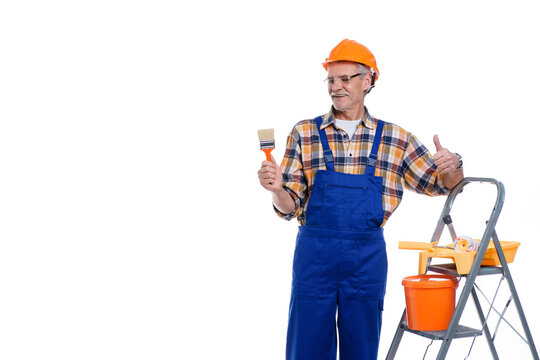 Professional builder, senior man in coverall and helmet ready for painting wall with roller, stay near stepladder, copy space and place for text