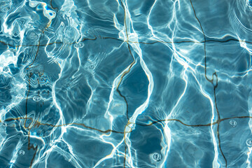 Obraz premium The texture of the pool water. Blue transparent water glows in the sun. Abstract natural background. Full-frame image of the pool. Bright turquoise background.