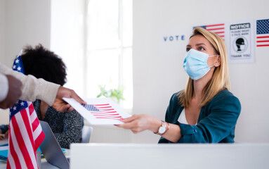 People with face mask voting in polling place, usa elections and coronavirus.