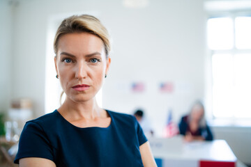 Portrait of serious woman in polling place, usa elections concept. - obrazy, fototapety, plakaty