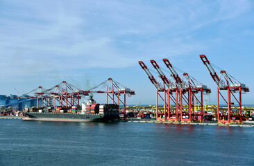 Container ship under gantry cranes in port of Kaohsiung, Taiwan. 