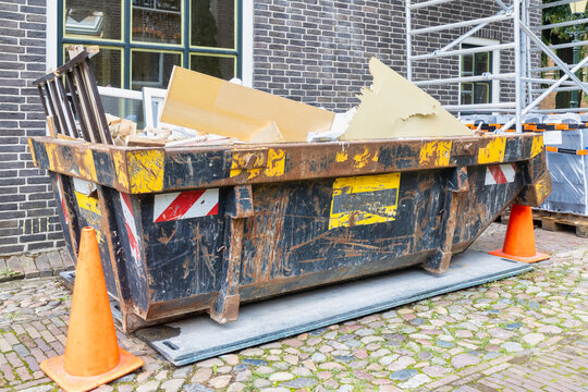 Dutch waste container in an old street on a home renovation construction site