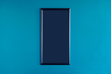 Black, blank frame hanging on the interior blue wall. Empty frame mock up.