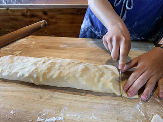 girl wearing apron cutting strudel dough on a chopping board in a mountain hut in trentino alto adige