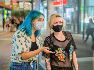 Shot of two women wearing medical masks talking to each other  - new normal