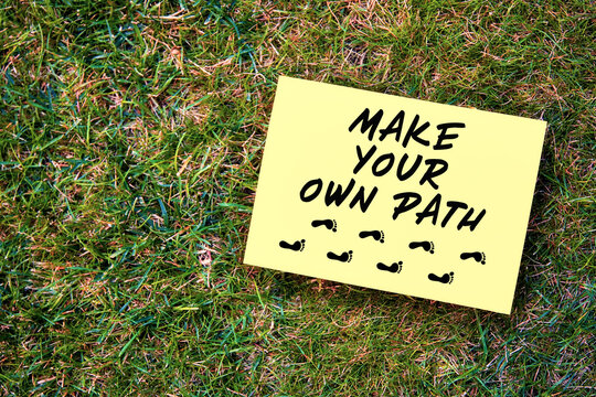 Make your own path message written on paper on green grass background. Motivational quote to create future in business or life.