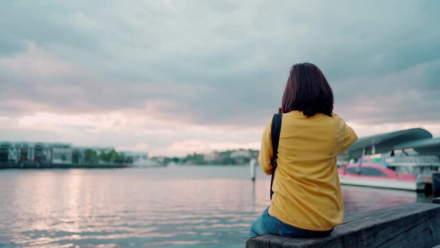 Asian woman tourist take photo of sunset at Daring Harbor Sydney , Australia