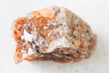 closeup of sample of natural mineral from geological collection - unpolished red Rock Salt (Halite) on white marble background from Perm Krai, Russia