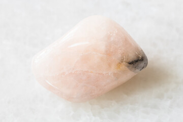 closeup of sample of natural mineral from geological collection - polished Morganite (Vorobyevite, pink Beryl) rock on white marble background from Mozambique