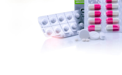 White tablets pills on white table and blurred pink-white capsule pills in blister pack. Pharmaceutical products. Pharmaceutical industry. Round and oval tablets pills. Healthcare and pharmacy.
