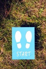 The word start written on paper with footprint on grass background. Inspirational quote to create a new future or new beginning in business or life.