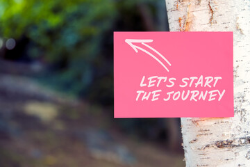 Let's start the journey motivational quote written on paper on a tree in nature.
