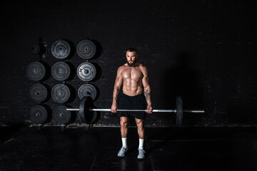 Young sweaty strong muscular fit man with big muscles holding heavy barbell weight and starting...