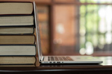 Book Stack and laptop computer on desk in library. copy space. education technology concept.