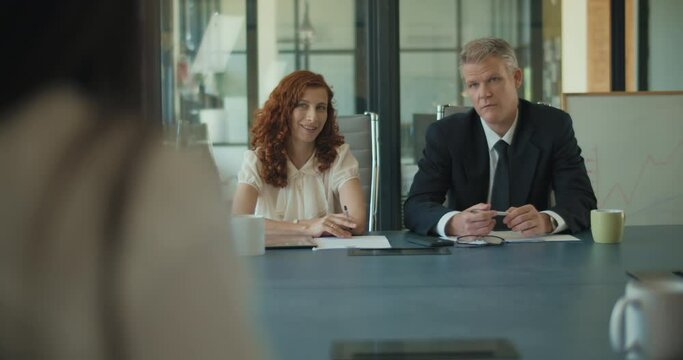 Two business people discuss project ideas with their clients in the office meeting room. Medium shot, slow motion. 