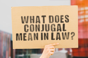The question " What does conjugal mean in law? " on a banner in men's hand with blurred background. Relationship. Separation. Wife. Family. Problem. Relation. Split