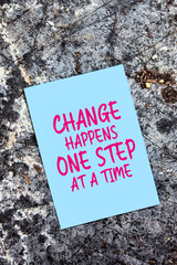Change happens one step at at time quote written on paper on rock or stone background in nature....