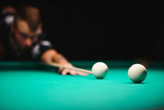 the player takes aim at the ball in Billiards