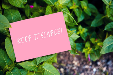 Keep it simple motivational quote written on pink paper on green garden and nature background....
