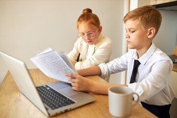 friendly kids couple behave themselves as adults, solve work problems together, look at laptop and documents, checking bills, making purchase online, freelance. children, people concept