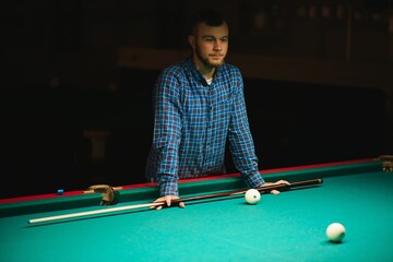 Fototapeta premium Young man playing billiard. Spending free time on gambling