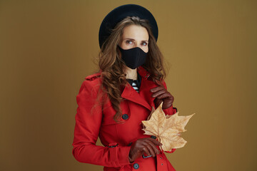 pensive trendy woman in red coat against brown background