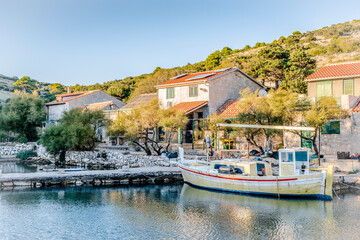 Fototapeta na wymiar Yellow wooden boat on the pier in the bay of the Adriatic sea near the fishing village in the evening in Lavsa, Croatia