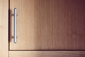Satin nickel plated door handle on an alder wood cupboard or cabinet.
