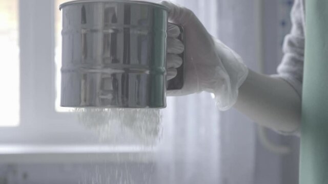 cook girl passes the flour through a sieve into a white mold