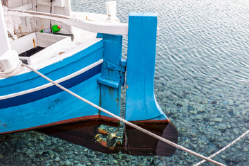 The stern of a wooden boat with a rudder and a propeller in the clear water of the Adriatic sea