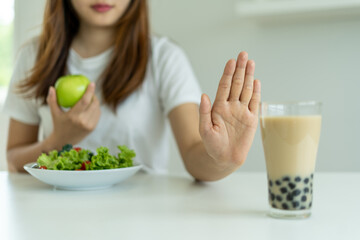 Healthy women do not eat pearl milk tea and choose apple and salad vegetables. Women reject foods and drinks but eat healthy vitamin food. Concept diet and good health.