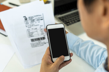 hand holding smart phone to scan QR code from invoice on papers for the bills. Scan, bar code online bill payment concept