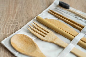 Eco friendly bamboo cutlery set in a case on a table. Zero waste concept. Set of bamboo cutlery in a case on a laying on a table. Spoon, fork, knife, toothbrush, tube and chinese sticks.