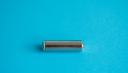 A single rechargeable battery on blue background. Silver alkaline AA battery for different device. Energy.