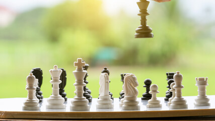 Business success leader concept, chess board game, player's hand, place white pawns on a board with blurred background and orange light.