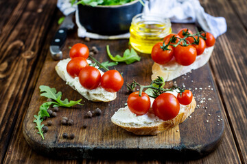 sandwiches with cheese and cherry tomatoes on a dark jar board on a wooden table close-up