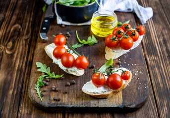 sandwiches with cheese and cherry tomatoes on a dark jar board on a wooden table close-up